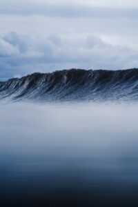 Picturesque view of dark blue seawater with large foamy wave under cloudy sky